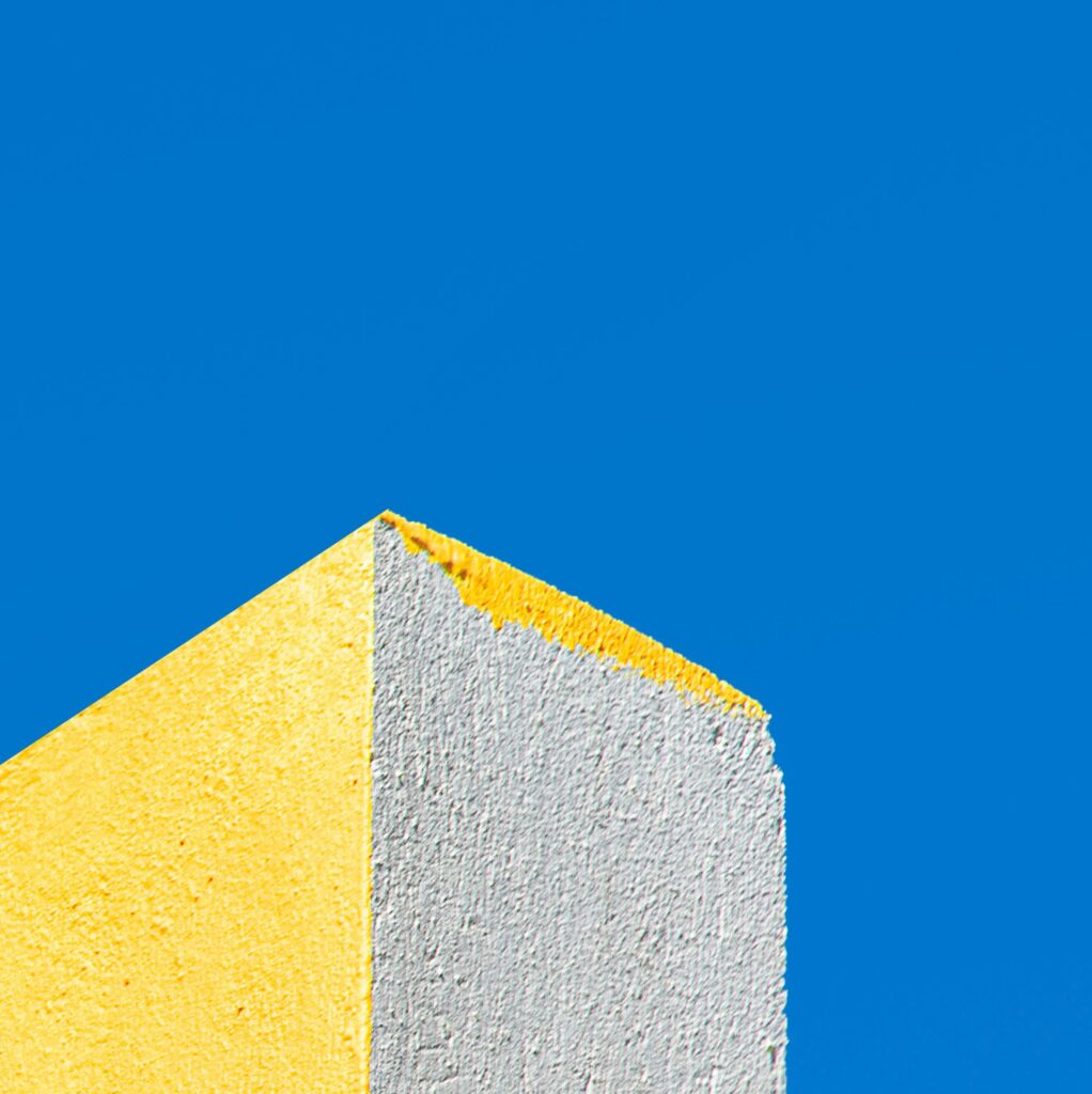 Une photo où la couleur dominante est le bleu, avec un petit coin de mur en bas à gauche en jaune et blanc.